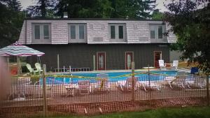 a house with a swimming pool with chairs and an umbrella at Edelweiss Ski Lodge in Ellicottville