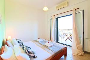 a bedroom with a bed with a view of a balcony at Kalimera Apartments in Vamos