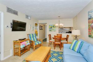 uma sala de estar com um sofá azul e uma mesa em LaPlaya 101E-Relax on your private lanai under the palms! em Longboat Key