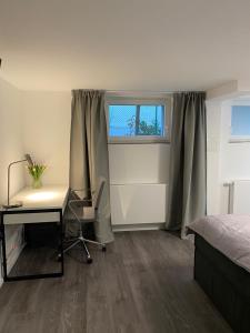 Schlafzimmer mit einem Schreibtisch, einem Bett und einem Fenster in der Unterkunft Luxus Appartement Kapstadt in Bergisch Gladbach
