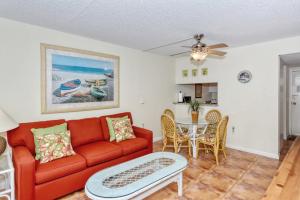 a living room with a red couch and a table at LaPlaya 104E Perfectly located near the path to the beach just steps from the pool in Longboat Key