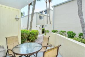 a patio with a table and chairs and palm trees at LaPlaya 104E Perfectly located near the path to the beach just steps from the pool in Longboat Key