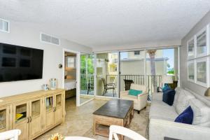 a living room with a couch and a tv at LaPlaya 202E Catch the gentle Gulf breezes on your private balcony beneath the swaying palms in Longboat Key