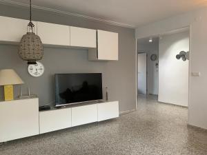 a living room with a television and white cabinets at Alicante Plage Muchavista Vu Mer Piscine Wifi Clim in Alicante