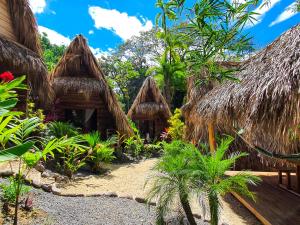 a group of huts with thatched roofs in a garden at Buena Onda Bungalows in Santa Teresa Beach