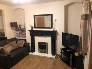 a living room with a fireplace and a television at Jrs place in Merthyr Tydfil