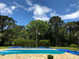 a large swimming pool in a park with trees at Chacara maravilhosa pertinho de Curitiba in Curitiba