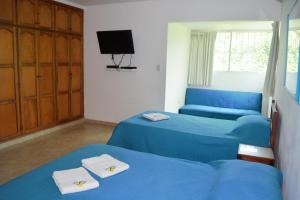 two beds in a room with blue sheets and a tv at Casa de Mony in Santa Marta