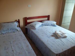 Dos camas en un dormitorio con toallas. en Candairó Hotel Pousada en Cananéia