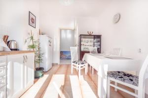 cocina blanca con mesa blanca y sillas en Ranko Apartments, en Risan