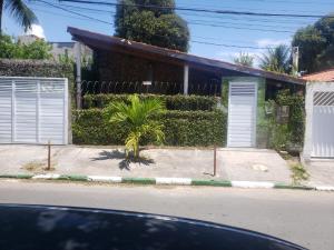 a house with white doors and a palm tree on the street at Itaparica - Vera Cruz 12 pessoas in Vera Cruz de Itaparica