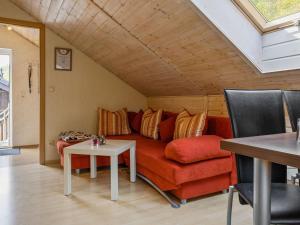 ein Wohnzimmer mit einem roten Sofa und einem Tisch in der Unterkunft Apartment with forest in Goldisthal Thuringia in Goldisthal