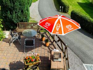 a red umbrella sitting next to a table and a bench at Apartment with forest in Goldisthal Thuringia in Goldisthal