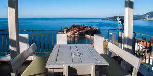 a table on a balcony with a view of the ocean at Hotel Adrović in Sveti Stefan