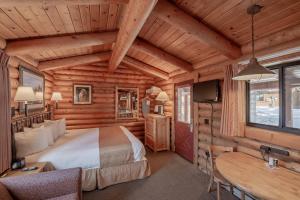 Cowboy Village Resort في جاكسون: غرفة نوم في كابينة خشب بها سرير ومكتب