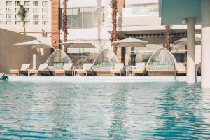 uma piscina com cadeiras e guarda-sóis num edifício em Coral Level at Iberostar Selection Cancun em Cancún