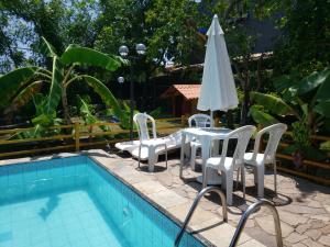 a table and chairs and an umbrella next to a pool at Itaparica - Vera Cruz 12 pessoas in Vera Cruz de Itaparica