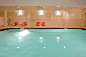 a swimming pool in a hotel with red chairs at Holiday Inn Express Hotel & Suites Fredericksburg, an IHG Hotel in Fredericksburg