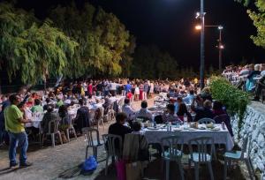 un gran grupo de personas sentadas en las mesas por la noche en Traditional Cretan House Lithostrati Karidi Village, en Karídhion