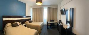 Habitación de hotel con 2 camas y escritorio en Hotel Real Rex en León