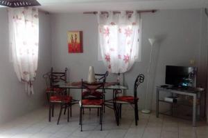 a dining room with a table and chairs and a television at Appartement de Standing en Martinique in Schœlcher