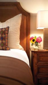 a bed with a pillow and flowers on a night stand at Best price ever The Sebastian at Vail 3BD 3BR in Vail +15 photos