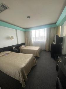een hotelkamer met 2 bedden en een flatscreen-tv bij Hotel Real Rex in León