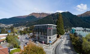 a building on a city street with mountains in the background at Ramada Queenstown Central in Queenstown