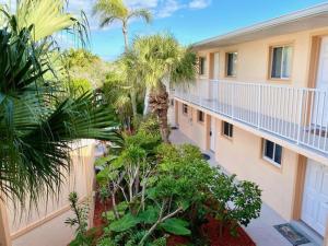an apartment building with palm trees in a courtyard at Cozy Canaveral Beach Condo! Next to NASA Launch Site in Cape Canaveral