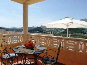 una mesa y sillas en un balcón con sombrilla en Sierra Verde Polop, en Polop