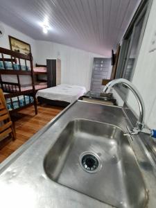 een keuken met een wastafel en een kamer met een bed bij Residencial Primo in Capão da Canoa