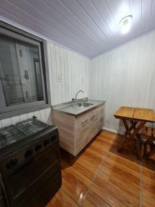 a kitchen with a sink and a stove and a table at Residencial Primo in Capão da Canoa +21 photos