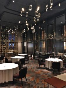 a dining room with tables and chairs and chandeliers at Tropicana The Residences KLCC by Vale Pine in Kuala Lumpur