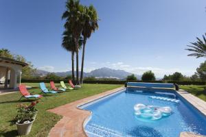 a swimming pool in a yard with chairs and trees at Casa Ponoig in Polop
