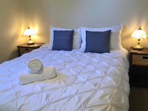 a large white bed with a towel on it at High Country Cottage in Twizel