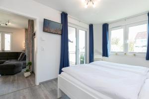 Schlafzimmer mit einem weißen Bett und blauen Vorhängen in der Unterkunft Ostseedomizil Ostwind in Kellenhusen