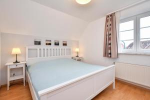 een witte slaapkamer met een bed en een raam bij Apartmenthaus Tiemann Wohnung 3 in Kellenhusen