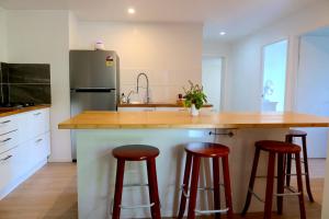 een keuken met een aanrecht met krukken en een koelkast bij Orchard Cottage - modern Australian Sunshine Coast holiday cottage on organic farm nr beach in Valdora