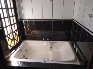 y baño con bañera blanca y azulejos negros. en Pousada Bella Praia, en Torres