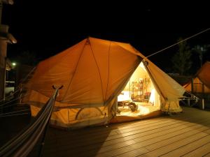 Fukiagehama Field Hotel في Ichikikushikino: خيمة كبيرة للجلوس على سطح السفينة في الليل