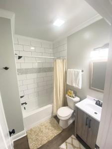 a white bathroom with a toilet and a sink at Bungalow Beach house 100 yards from the beach in Bay Saint Louis