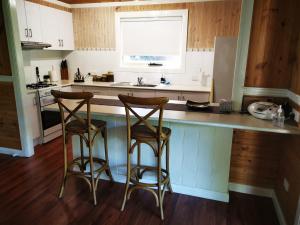 a kitchen with two bar stools at a counter at Peaceful cabin in a rural setting 2km from CBD in Tamworth