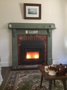 a living room with a fireplace and a fire place at Rosedale Cottages in Taranna