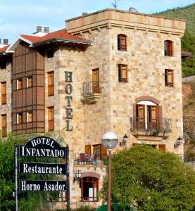 un gran edificio de piedra con un cartel delante en Hotel Infantado, en Ojedo