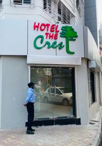 een man die voor een hotel staat het enge bord bij Hotel The Crest in Calcutta