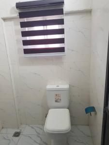 a bathroom with a white toilet and a window at ULOM 1condos apartment in Owerri
