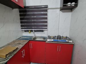 una piccola cucina con armadi rossi e lavandino di ULOM 1condos apartment a Owerri