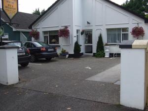 a white building with cars parked in a parking lot at Windway House in Killarney