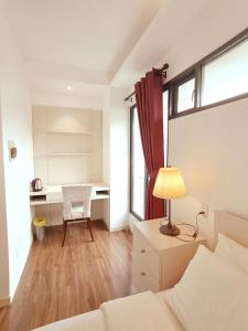 um quarto com uma cama e uma escrivaninha com um abajur em Citihouse Ho Chi Minh Apartment em Cidade de Ho Chi Minh