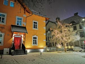 un edificio naranja con una puerta roja en la nieve en Villa Maria - Suiten & Appartement, en Kufstein